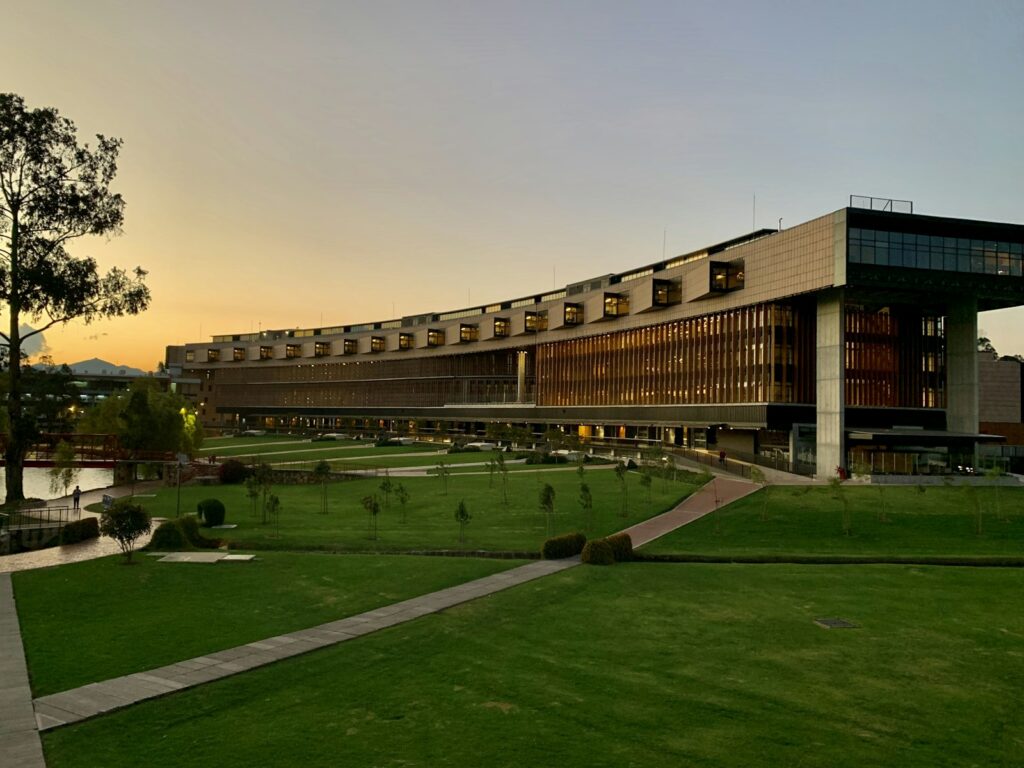 Edificio universitario de ladrillo junto a una zona verde, imagen para la guía de la Universidad Complutense de Madrid